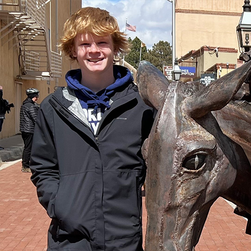 A young man posing next to a statue